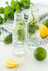 Infused water with citrus and mint in glass bottles on wooden ba