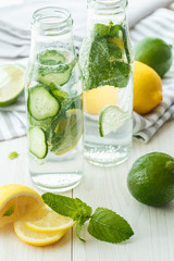 Infused water with citrus and mint in glass bottles on wooden ba