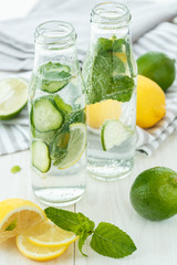 Infused water with citrus and mint in glass bottles on wooden ba