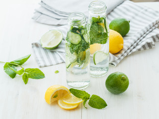 Infused water with citrus and mint in glass bottles on wooden ba