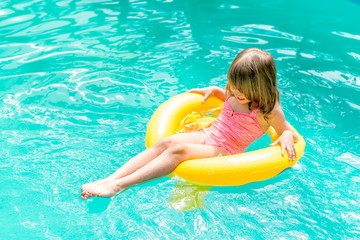 Happy child playing in swimming pool to rescue circle yellow