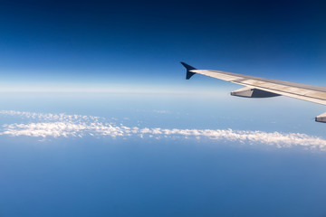 Fototapeta premium Wing of airplane flying above the clouds in the sky