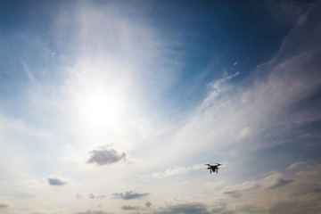 Done quad copter flying hovering in the blue sky, silhouette