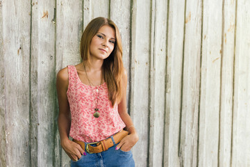 Fototapeta premium Fashion young blond woman in pink Tshirt over pale wooden background