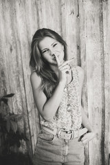 Fototapeta premium Black and white portrait of attractive teenage girl with finger on lips, secret gesture, young pretty woman