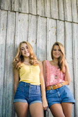 Two happy female friends smiling over pale wooden background