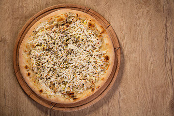 Pizza with chicken, four cheese and zucchini served on wooden pl