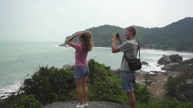 Girl Combs Her Curly Hair Posing for an Operator on a Cliff Overlooking the Bay with Storm Waves. Slow Motion