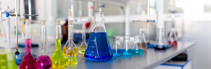 Laboratory table piled tubes with colored liquid, colored reagents in flasks and test tubes