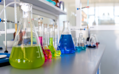 Laboratory table piled tubes with colored liquid, colored reagents in flasks and test tubes