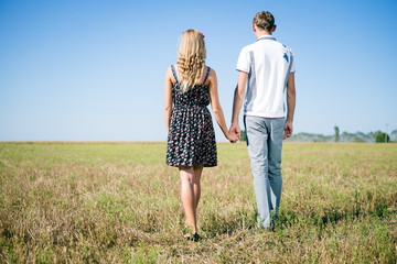 Happy smiling young hippie couple hugging outdoors from back