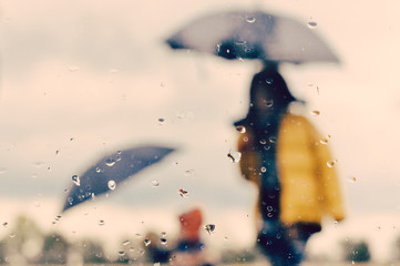 Mother and son outdoors under umbrella silhouette through wet window