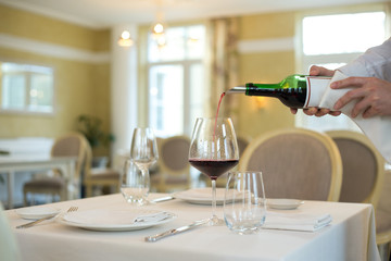 served table restaurant wine being poured into glass, white tablecloth, plates and cutlery