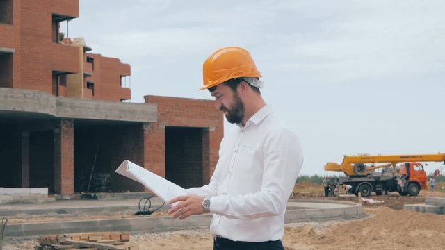 Architect looking at blueprints at a building site. 4K.