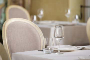 Empty glasses and plates installed in the restaurant, the restaurant served table, white tablecloth and wine