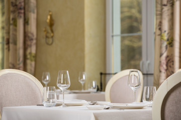Empty glasses and plates installed in the restaurant, the restaurant served table, white tablecloth and wine