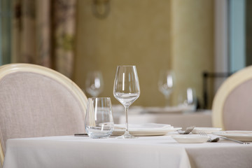 Empty glasses and plates installed in the restaurant, the restaurant served table, white tablecloth and wine
