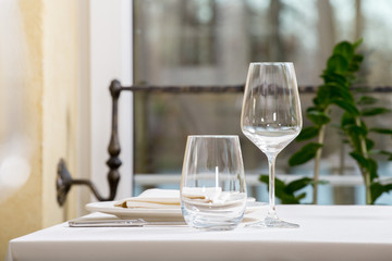 Empty glasses and plates installed in the restaurant, the restaurant served table, white tablecloth and wine