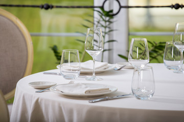 Empty glasses and plates installed in the restaurant, the restaurant served table, white tablecloth and wine