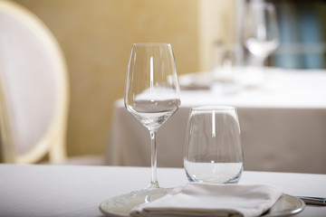 Empty glasses and plates installed in the restaurant, the restaurant served table, white tablecloth and wine