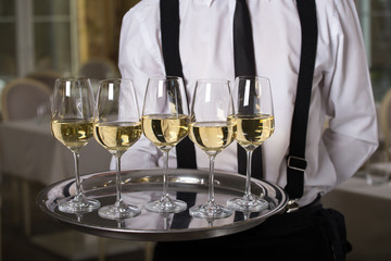 white wine glasses on a tray waiter tray with white wine, a lot of glasses