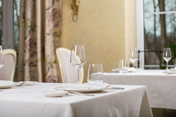 Empty glasses and plates installed in the restaurant, the restaurant served table, white tablecloth and wine