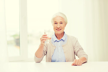 Fototapeta premium happy senior woman with glass of water at home