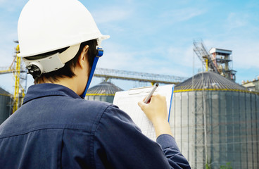 engineer is recording data with power plant background