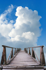 Fototapety  Wooden bridge and blue sky full of white clouds in summer