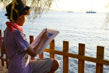 Boy drawing sea and fishes at sunset