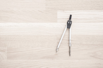 Compass used for design work or architecture lying on wooden desktop. Concept of geometry, drafting...