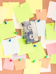 Vintage cassette tape on notice board, message of office party. Concept image of sound communication or 80s retro reminder with copy space.