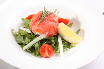 Red fish on Arugula in white plate