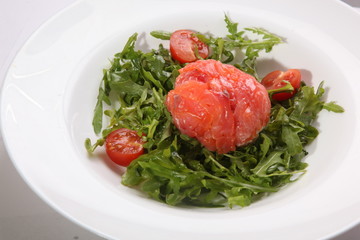 Red fish on Arugula in white plate