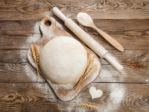 Fresh dough on cutting board with a rolling pin