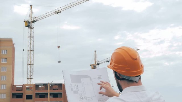 Chief architect at construction site. Chief architect in a hard hat at construction site looking at the plan, blueprint. HD.