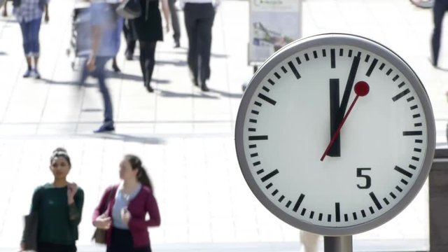 Time lapse of a busy business street with a clock in focus on a bright sunny day