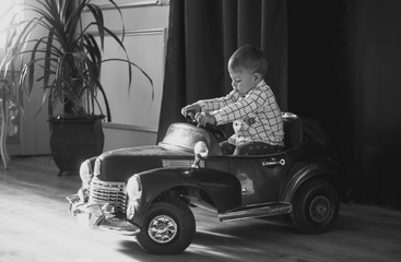 Black and white image of 1 year old boy riding big toy car