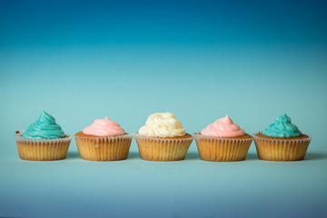 Colorful freshly baked cupcakes in row over blue background