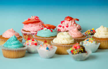 Homemade colorful cupcakes and candies on blue background