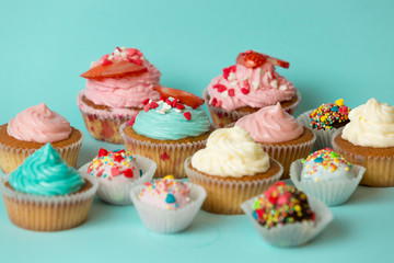 Closeup of tasty freshly baked cupcakes and colorful candies ove