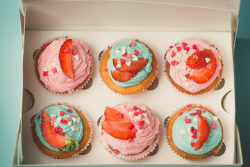 Closeup of six decorated cupcakes in paper gift box