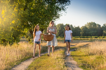 Fototapeta premium Beautiful mother walking to picnic with her two daughter