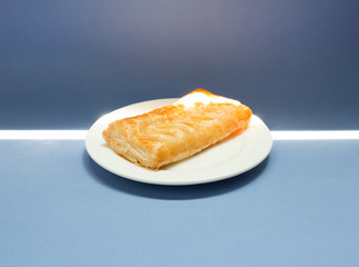 Homemade Corn Pie on white plate on blue background. Sunshine from the window.