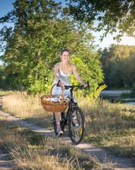 Smiling woman riding bicycle by the river at sunny day