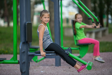 Fototapeta na wymiar Cute little girls is engaged in sports equipment outdoor.