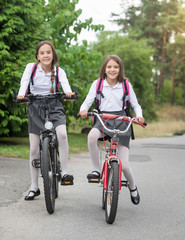 Fototapeta na wymiar Happy girls in uniform riding to school at morning