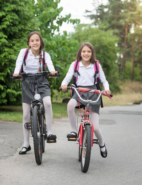 Happy girls in uniform riding to school at morning