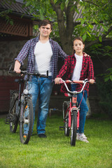 Young man and teen girl with bicycles having fun at park