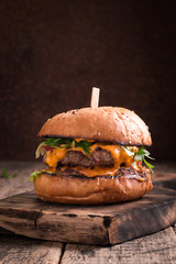 Tasty grilled burger with lettuce and mayonnaise ,on a rustic wooden table